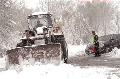 一辆铲车在交警的指挥下正在清理路面积雪。昨天，延庆县遭遇了52年来最大降雪。新华社发