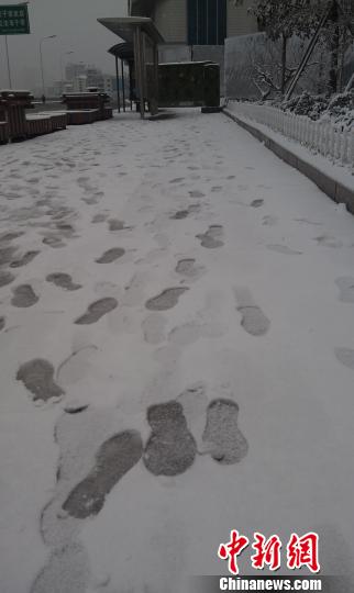 图为雪中行人留下的脚印，雪底下是融化了的雪水。宋锦丰摄
