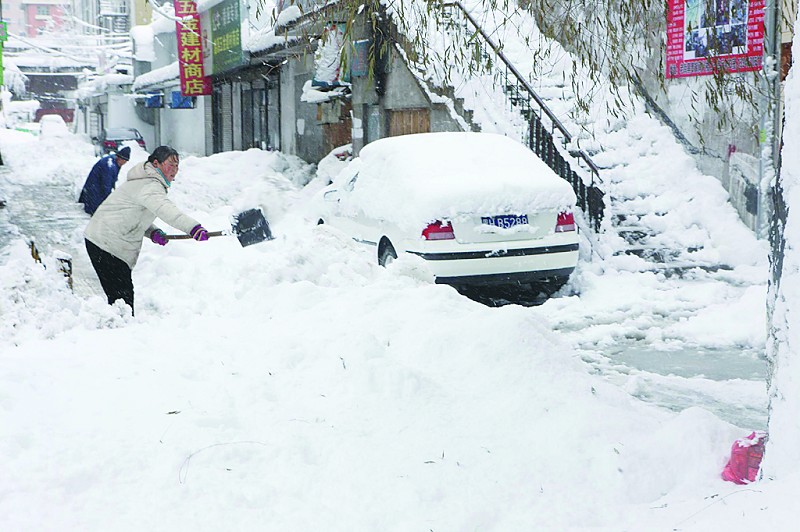 11月13日,居民在黑龙江省鹤岗市街头清理积雪.