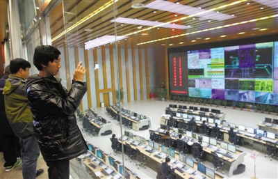 昨日，北京市交通运行监测调度中心旅游开放日活动上，一位市民隔着玻璃用手机拍摄北京交通运行监测工作。新京报记者 薛�B 摄