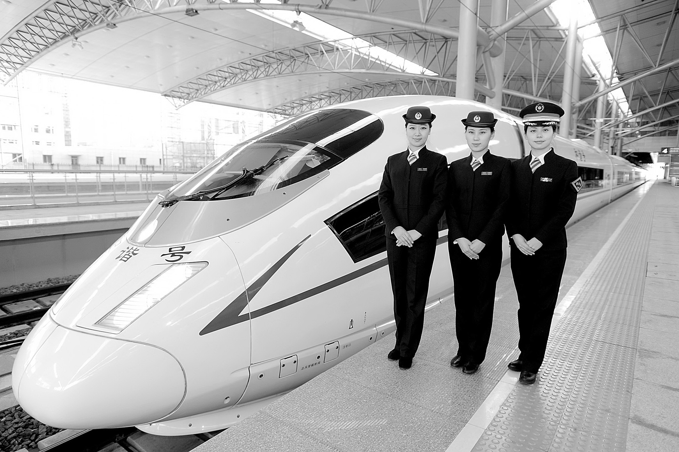 11月26日,沈阳铁路局的高铁乘务员在一辆哈大高铁列车旁站立.
