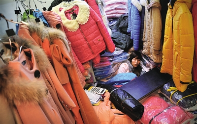 22日上午11点,购物的人潮退去,一位店倒在衣服堆里睡着了