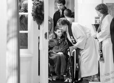 14日，在美国康涅狄格州纽敦市一所教堂，牧师拥抱为枪击事件死难者祈祷的居民。新华社记者 王 雷摄