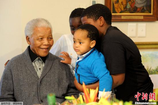 资料图：当地时间2012年7月18日，南非东开普省，前南非总统曼德拉在家中和家人庆祝自己的94岁生日。图为曼德拉和自己的重孙在一起。