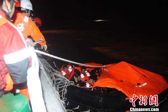 图为遇险、在救生筏上待救的15名船员正被东海救助局的救助船救起。 东海救助局提供。 摄
