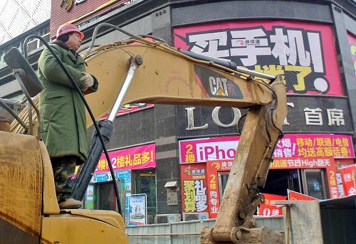 1月2日，在德化街工地上，施工人员站在挖掘机上观看附近的商业促销活动。新华社记者 王颂 摄