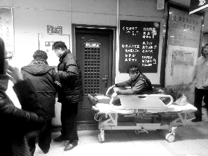 受伤工人小王坐在病床上候诊。费昕/摄