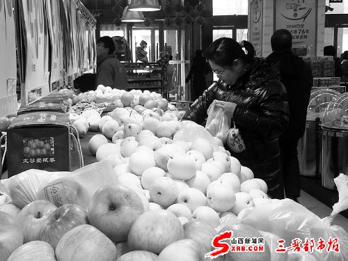 美特好超市水果货架前,一市民正在挑选水果。