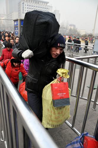 1月8日,一名外来务工人员背着行李在太原火车站准备进站.