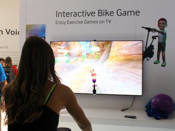 三星的智能电视可以下载游戏，也可以移动控制。这是某人正在演示用一个静止单车来玩游戏的场面。