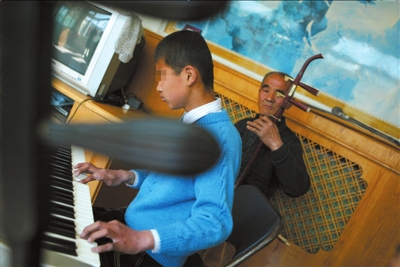 2009年4月4日，王玉民与寄养在自己家中的两个残疾孩子一起表演。（资料图片） 本报记者王苡萱摄