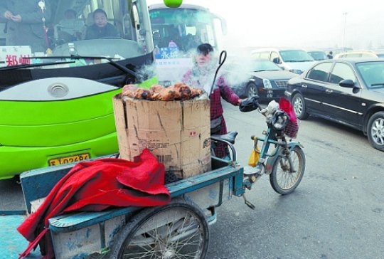 小商贩在向被堵在路上的司机和乘客兜售烤红薯