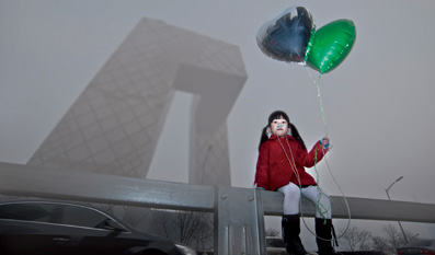 2013年1月13日下午，北京东三环附近，空气污染严重，一个小女孩手持气球坐在围栏上。