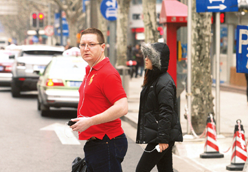 左图:昨天下午,一位老外身着短袖t恤穿过马路,和身旁一位穿棉袄的行人