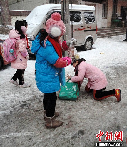 1月21日，河南郑州，小学生在冰天雪地里行走前去上学，由于路面结冰湿滑，致使小学生多有摔倒。从19日夜至20日，中国多地区普降大雪。中新社发 王中举 摄