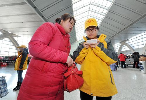 1月25日，在宁夏银川火车站，春运志愿者曹绒在帮助一位旅客寻找正确的候车地点。新华社记者 彭昭之 摄