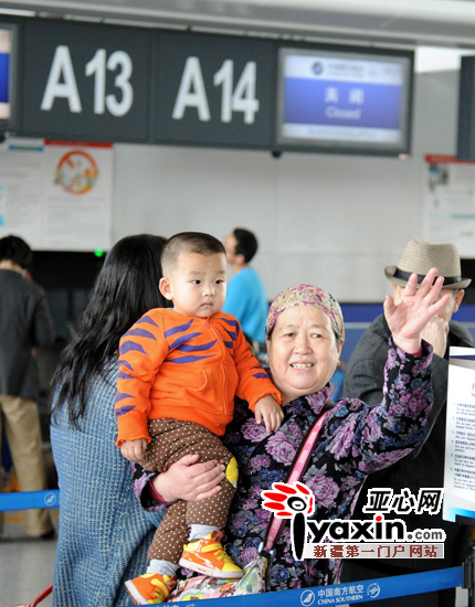 图为：在乌鲁木齐国际机场里，旅客挥手与亲人告别。亚心网记者 李铁军 摄