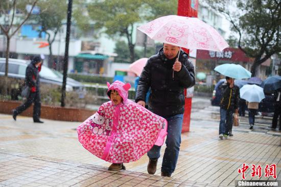 2月7日中午，上海下起了大雪。图为一位小朋友穿着hello kitty 的雨衣和她爸爸走在雪中。东方IC 版权作品 请勿转载