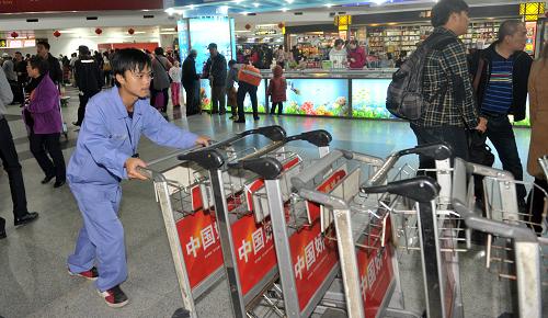 2月10日,在海南海口美兰国际机场,工作人员蔡夫才在整理行李推车.
