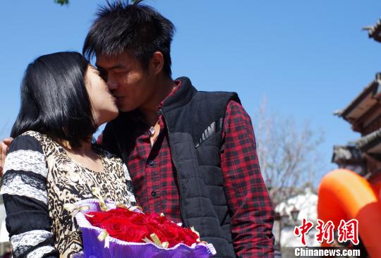 图为来云南旅游的陈小姐在收到男友赠送的玫瑰后与男友在大街上相拥而吻。 向丹 摄