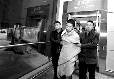 两名便衣警察押解着奚某抵达首都机场。本报记者 欧阳晓菲 摄