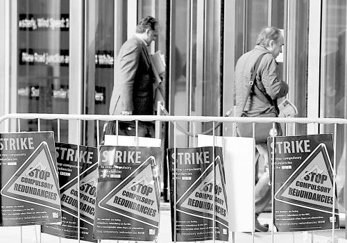 18日，两名男子从BBC罢工标语前经过。