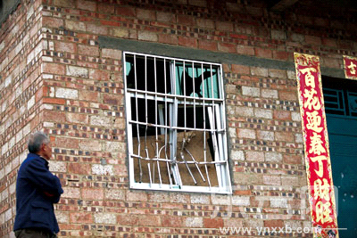 一名村民看着被砸坏的防盗笼。