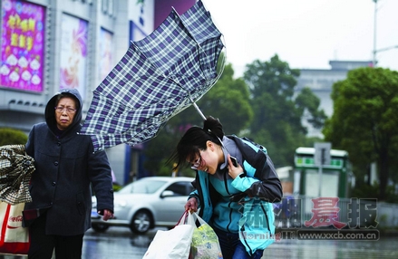 一位女士的雨伞被大风吹翻了