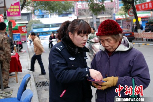 3月2日，桂林民警在向老奶奶介绍安全防范常识手册上的内容。当日，桂林市公安局秀峰分局在桂林市中心广场开展“打盗抢保民安”暨学雷锋为民服务。中新社发 伍峰 摄