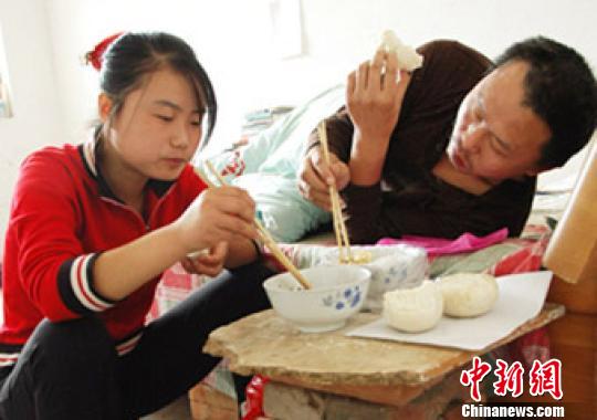 背着父亲上学的赵青和父亲一起吃饭。 张义力 摄
