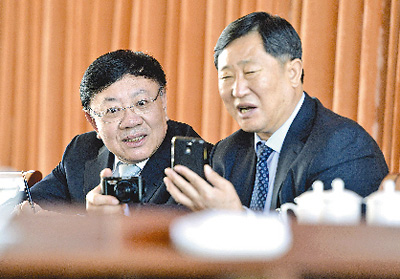 王文良代表(左)和高宝玉代表用手机和相机