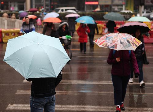 3月12日,路人在雨中撑伞经过幸福大街路口.新华社发(李方宇摄)