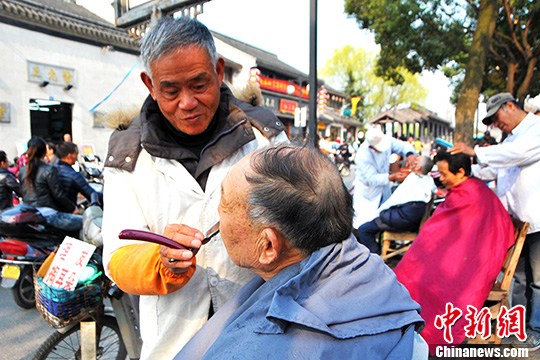 图为老师傅正在认真地给顾客理发.王思哲摄来源中国新闻网)