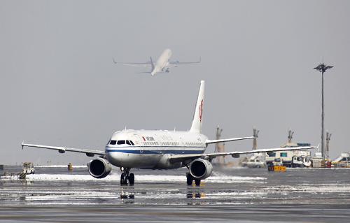 3月20日，在北京首都机场，出港航班（上）完成除冰作业后起飞。新华社发（荆雷 摄）