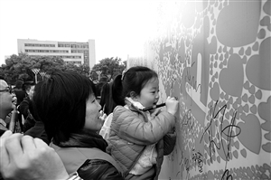昨日，中山广场，一名6岁的小志愿者在“告别中国式过马路”签名版上写下自己的名字