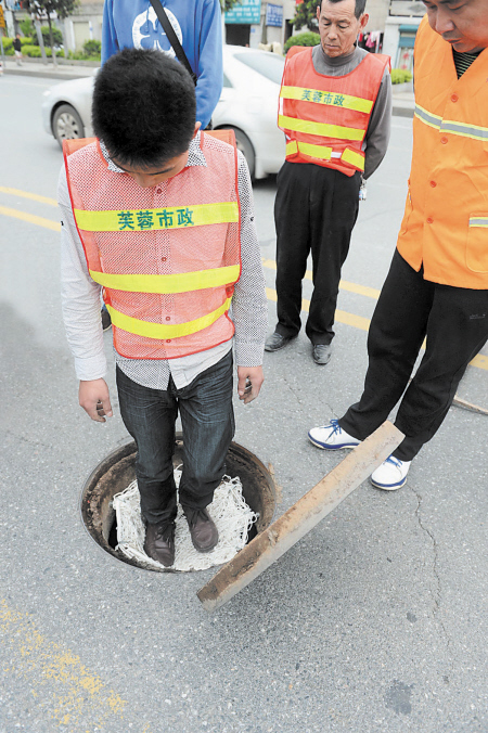昨日，芙蓉区市政工作人员站在营盘东路一个刚安装完毕的留泥井防坠网上试承重情况。