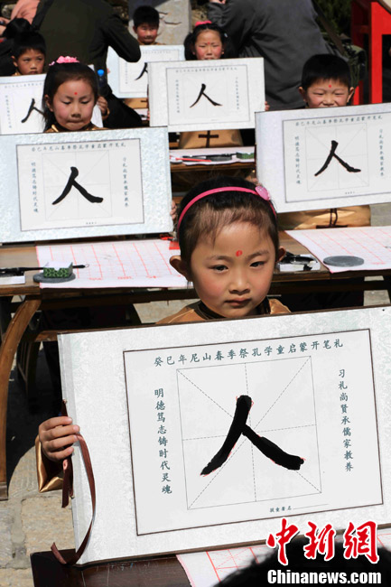 学童开笔礼现场,数十名曲阜学童在老师的指导下书写第一个大字"人"