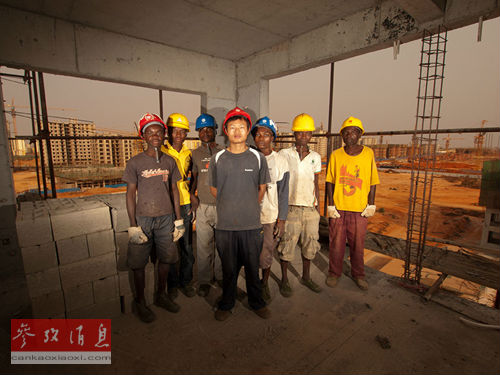 安哥拉:尚未完工的一栋建筑里,一名中国管理者同身后的安哥拉工人合影