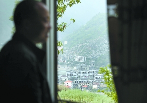 刘斌站在自家窗口,窗外是老北川的废墟.