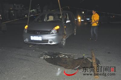 路面塌陷出一个直径约两米深约两米的大坑，出事的小汽车被吊车吊离 东莞时报记者 雷元全 摄