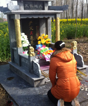 吴晓雅跪在丈夫的墓前哭诉。墓碑是以他们儿子的名义立的。
