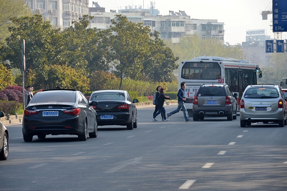 三名行人在车流中奔跑横穿马路.姚宏 摄