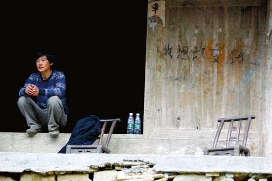 4月12日，村民坐在门口，旁边的木墙上写有五个字“我想改变路”。