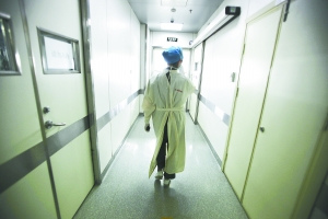 地坛医院医护人员穿着布制隔离衣走过隔离区。