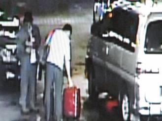 白色上衣的男子从车上取下一大一小的行李箱，同车的戴黑帽男在一旁，警方怀疑两人就是炸弹客。 图／记者杨德宜翻摄