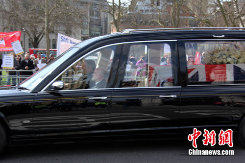 4月16日下午，英国前首相撒切尔夫人的遗体被移送至英国国会大厦内的圣玛丽教堂。图为运送撒切尔夫人遗体的车辆，透过车窗可以看到灵柩上覆盖着英国国旗。撒切尔夫人的葬礼将于4月17日举行。