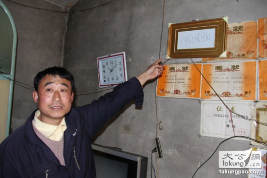 图说:\"的哥\"郭立新在自家门口展示他所称习近平为他题写的\"一帆
