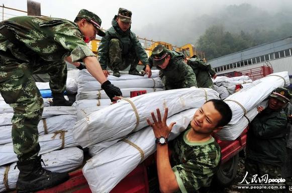 在四川省宝兴县灵关镇救灾物资集中点,武警四川总队南充支队的官兵在搬运救灾帐篷。