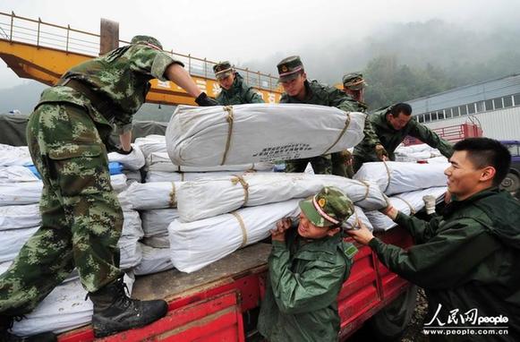 在四川省宝兴县灵关镇救灾物资集中点,武警四川总队南充支队的官兵在搬运救灾帐篷。
