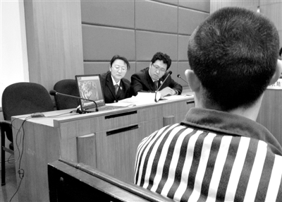 庭审时，公诉人当庭播放监控录像。近日，一服刑人员在监狱将同监犯人打成轻伤，被加刑10个月。新京报记者 张媛 摄